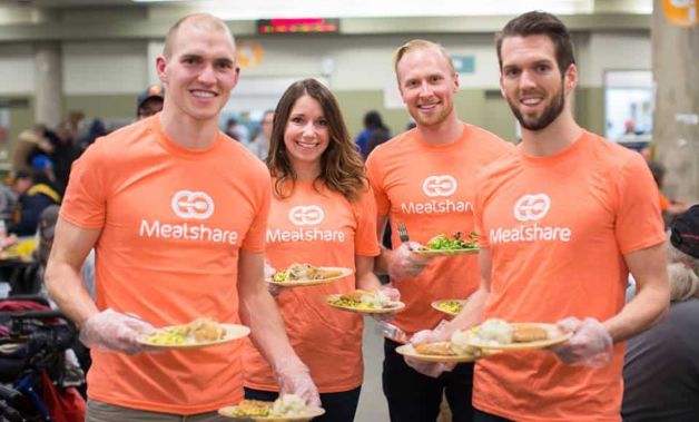 People with food in their hands in Mealshare T-shirt